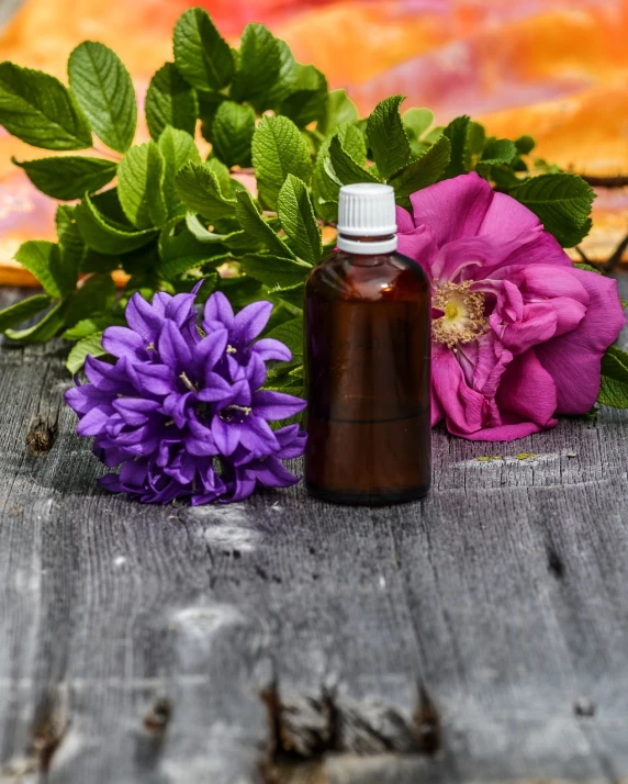 a bottle of essential oil next to a bunch of flowers, a picture, by Rhea Carmi, shutterstock, a wooden, details and vivid colors, version 3, outdoor photo