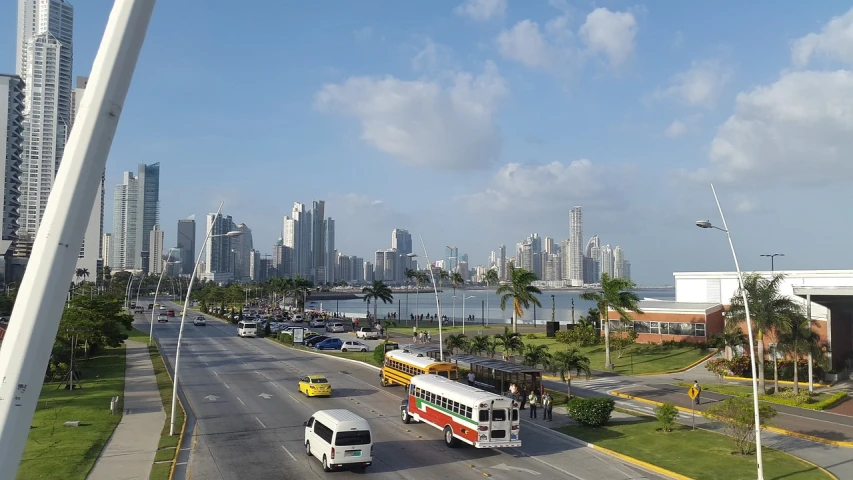 a city street filled with lots of traffic next to tall buildings, by Ceferí Olivé, tropical coastal city, all buildings on bridge, bus, grass field surrounding the city