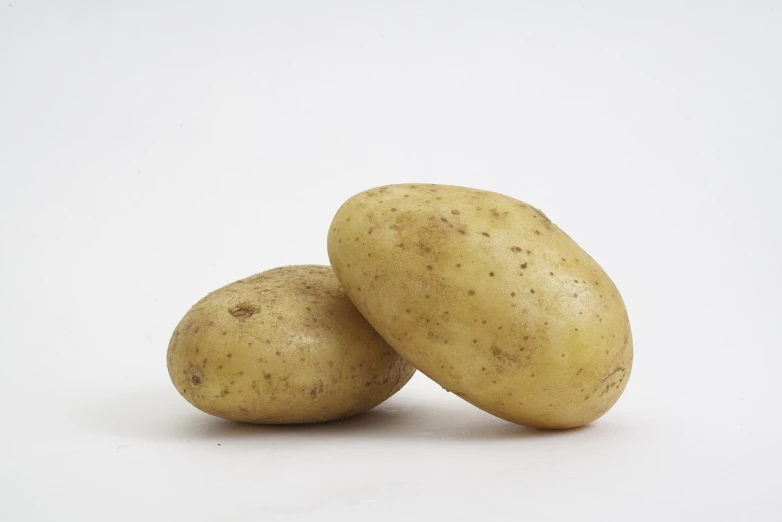 two potatoes sitting next to each other on a white surface, a picture, by John Murdoch, flash photo, stock photo