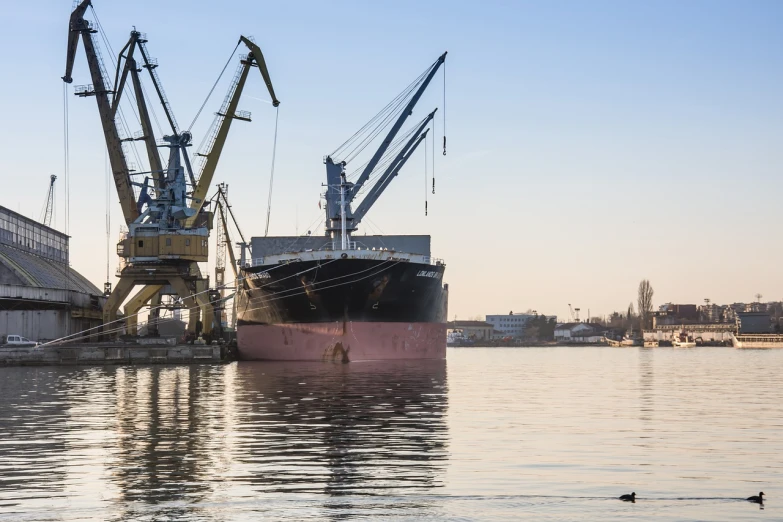 a large boat sitting on top of a body of water, a portrait, by Robert Koehler, shutterstock, huge machine cranes, warsaw, ships in the harbor, high quality product image”