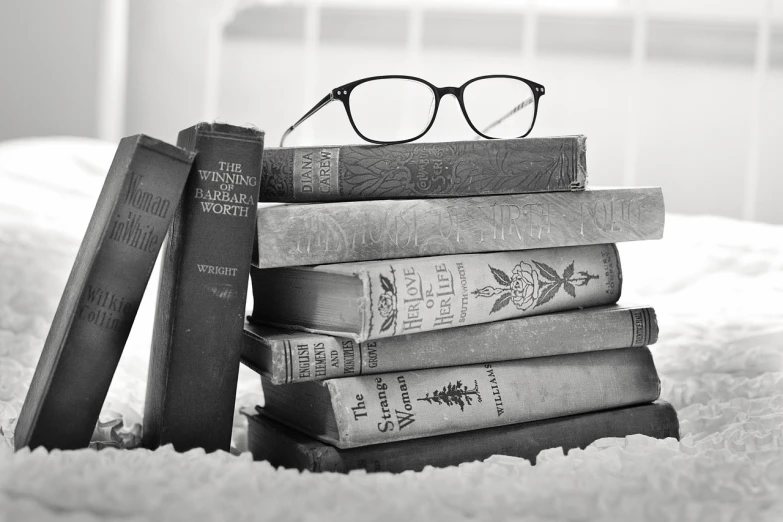 a stack of books sitting on top of a bed, a black and white photo, by Maksimilijan Vanka, pixabay, specimens in glasses, fairytale, well-detailed, by greg rutkowski