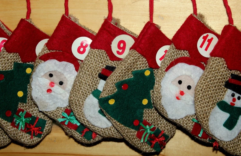 a group of christmas stockings sitting on top of a wooden table, a photo, flickr, countdown, close up face detail, hessian cloth, n - 9