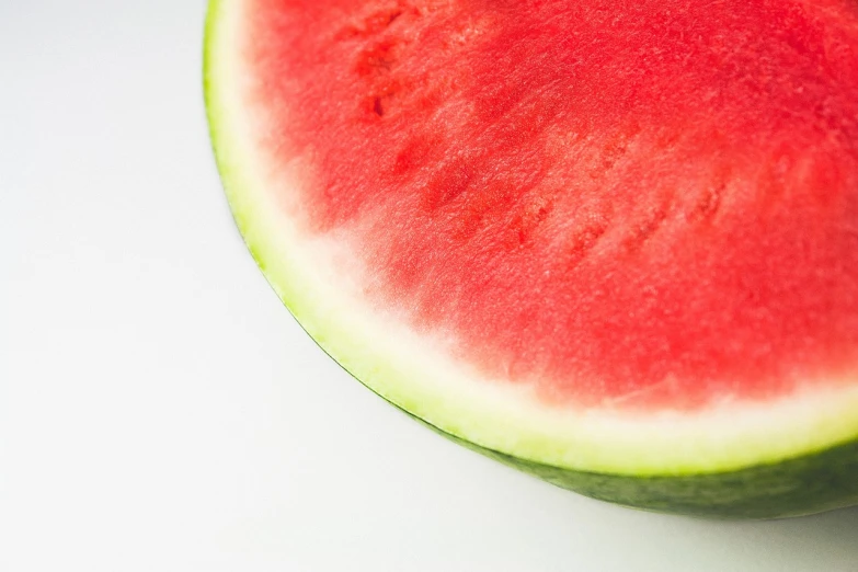 a slice of watermelon sitting on top of a table, a picture, by Kazimierz Wojniakowski, hurufiyya, istockphoto, over-shoulder shot, with a white background, shot on a 9.8mm wide angle lens