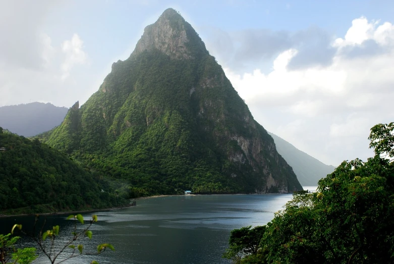 a body of water with a mountain in the background, a photo, caribbean, giant imposing mountain, pyramid surrounded with greenery, great light and shadows”