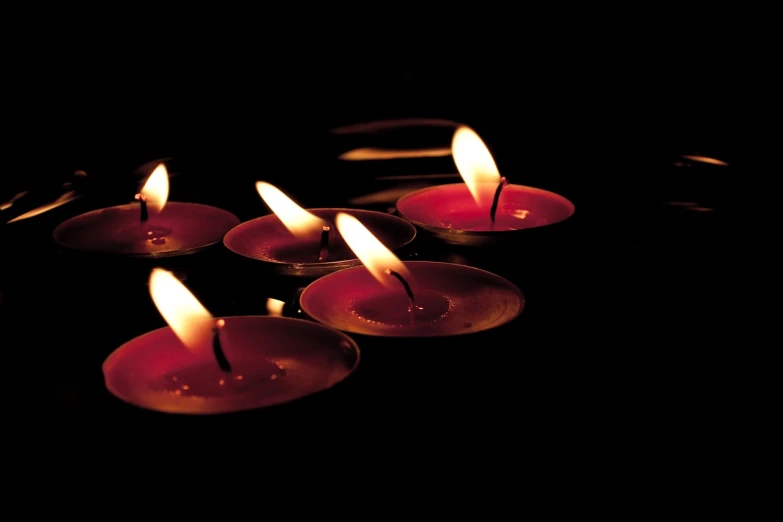 a group of lit candles sitting on top of a table, a photo, hurufiyya, volumetric lighting. red, high res photo, portlet photo, floating lights