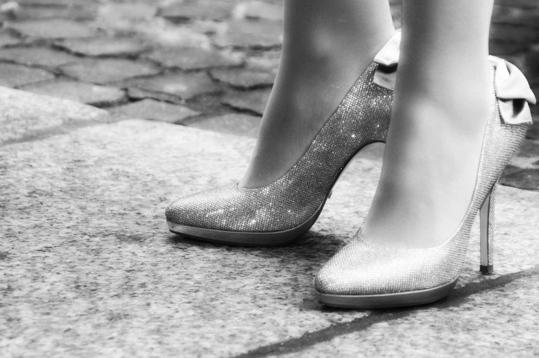 a black and white photo of a woman's shoes, by Thomas Häfner, trending on pixabay, glittery, golden and silver colors, street of paris photography, two legs