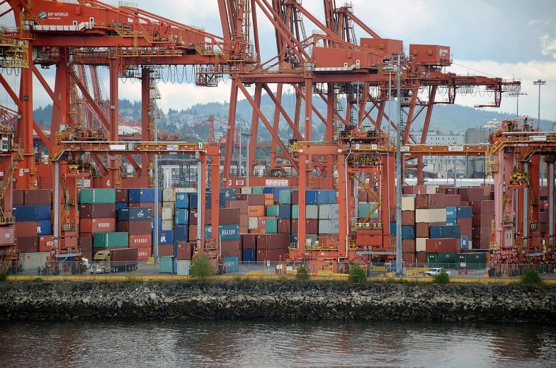 a large container ship sitting on top of a body of water, by Matt Stewart, huge machine cranes, vancouver, medium closeup shot, trading illegal goods