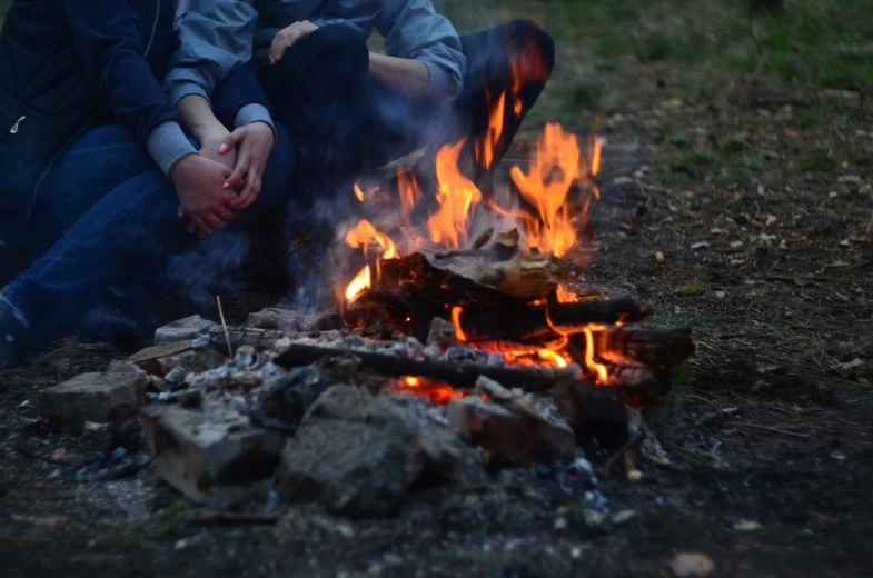 a couple of people sitting next to a fire, a picture, by Niko Henrichon, sitting with wrists together, jakub kasper, not cropped, fim still