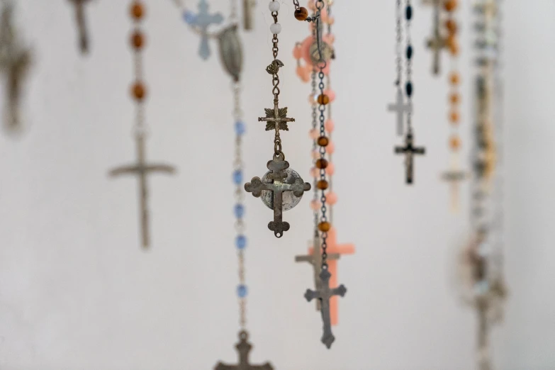 a bunch of crosses hanging from a wall, unsplash, folk art, close up shot of an amulet, a delicate, enamel, diana levin