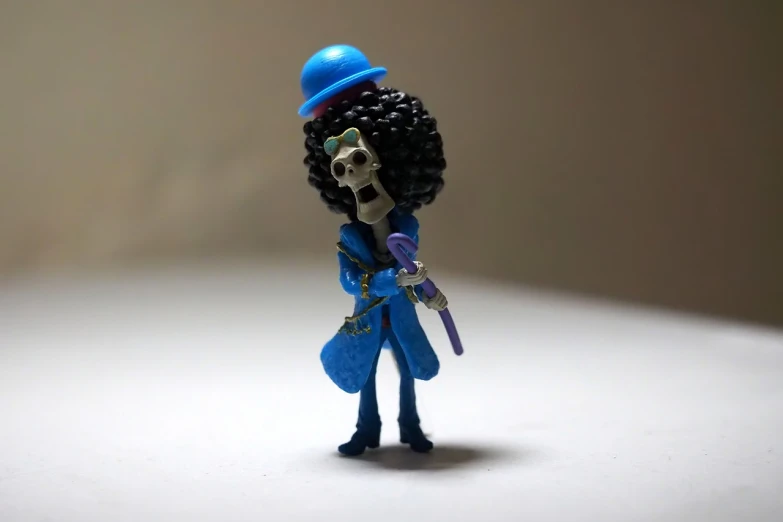 a close up of a toy figure on a table, concept art, inspired by Bartolomeo Vivarini, vanitas, heavy blues rock, with afro, wearing sombrero, highly detailed full body