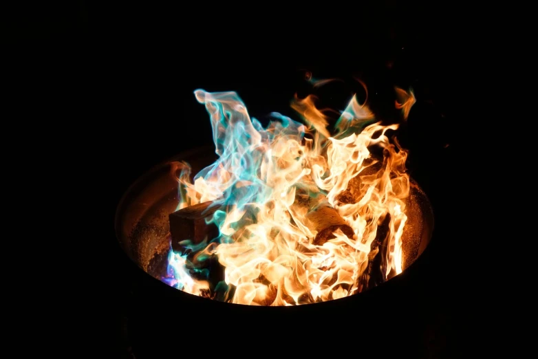 a close up of a fire in a frying pan, a picture, luminescent colors, outdoor photo, strong blue and orange colors, flash photo