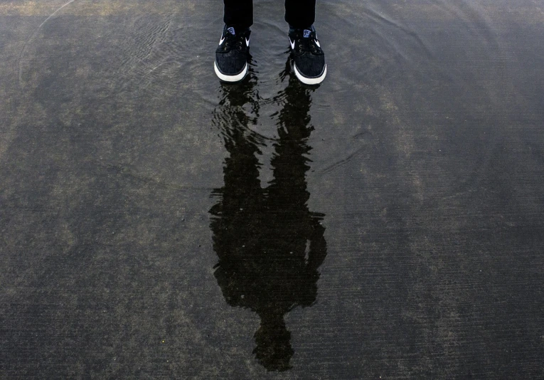 a person standing in a puddle of water, a picture, by Matt Stewart, sneaker photo, symmetry!!!, silhouetted, afp