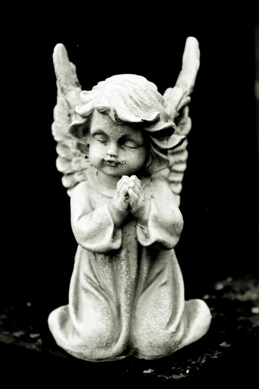 a black and white photo of a statue of an angel, a statue, by Marie Angel, prayer hands, 33mm photo, cherub, full front view