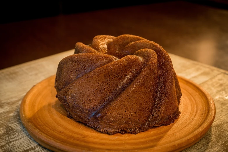 a bundt cake sitting on top of a wooden plate, by Aleksander Gierymski, pixabay, some wrinkled, azamat khairov, 2 4 mm iso 8 0 0, wikimedia commons