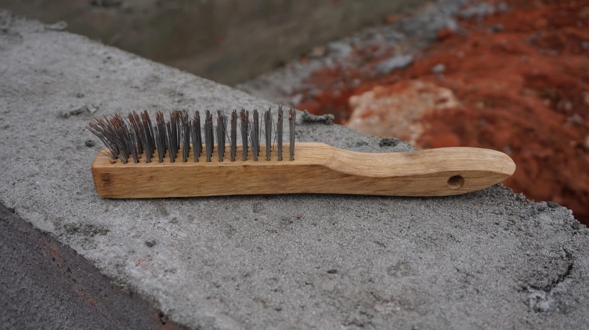 a wooden comb sitting on top of a cement slab, inspired by Mirko Rački, flickr, long metal spikes, stipple brush technique, made of wire, outdoor