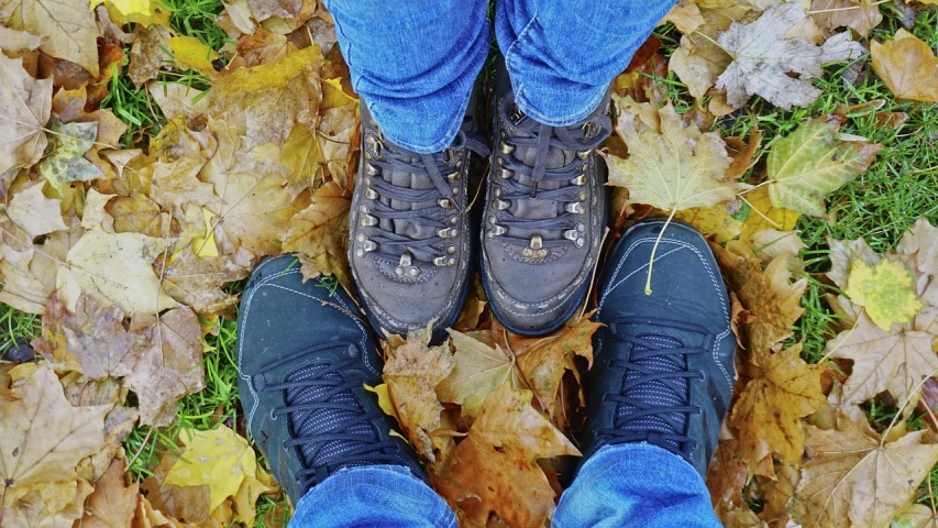 a person standing on top of a pile of leaves, a photo, pixabay, doc marten boots, adult pair of twins, they are close to each other, tourist photo