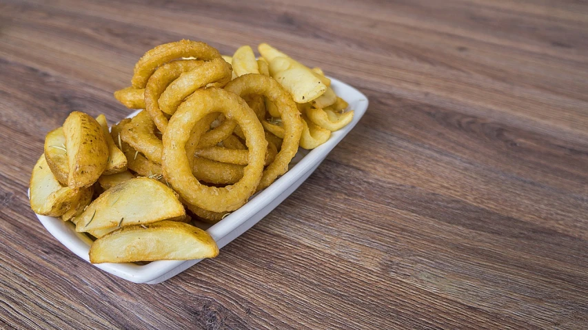 a plate of onion rings on a wooden table, a stock photo, inspired by Chippy, version 3, square, french fries, squid