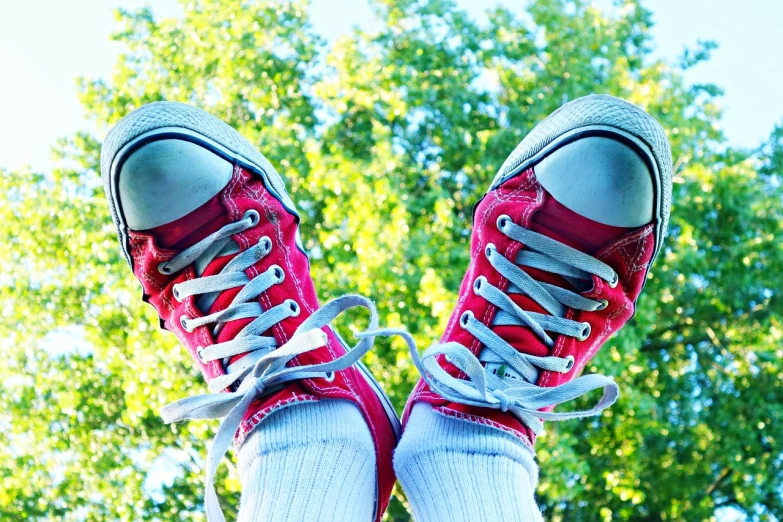a pair of red sneakers sitting on top of a skateboard, by Jan Rustem, mid view from below her feet, on trees, vivid colors!, converse