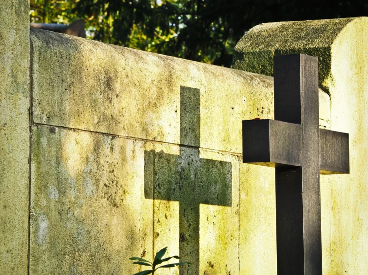 a close up of a cross on a stone wall, pexels, symbolism, graveyard tombstones, backlighted, mausoleum, 555400831