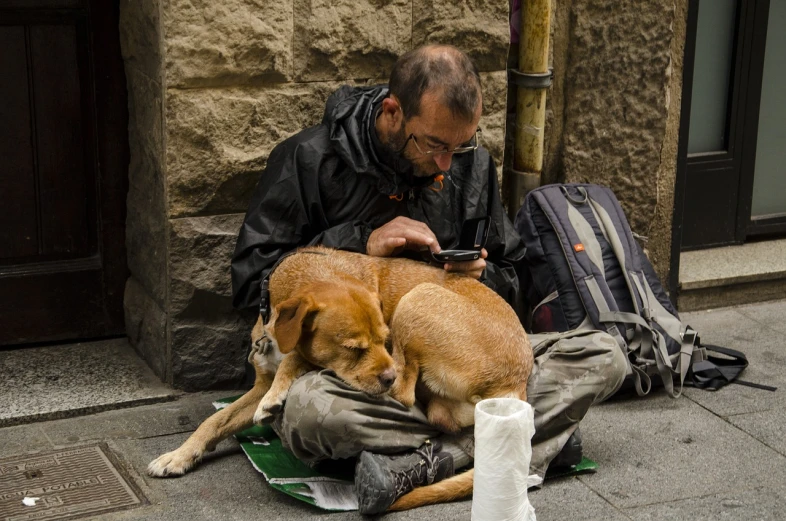 a man sitting on the ground with a dog, a photo, by Luis Molinari, shutterstock, cellphone, hunger, highly detaild, barcelona