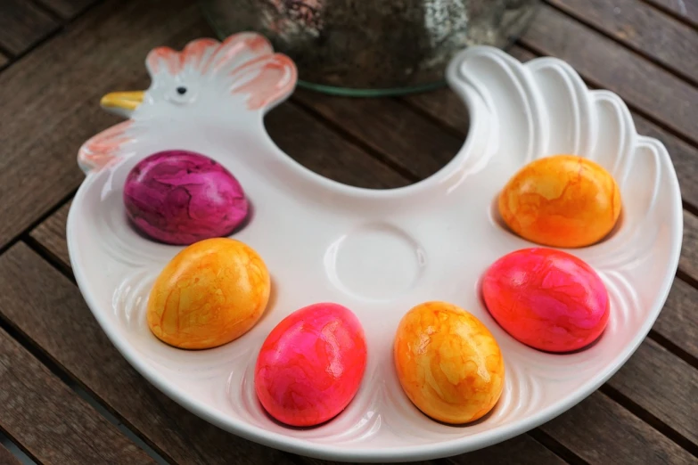 a white plate topped with eggs on top of a wooden table, a pastel, inspired by Károly Patkó, process art, candy treatments, duck, pink and orange colors, colored marble