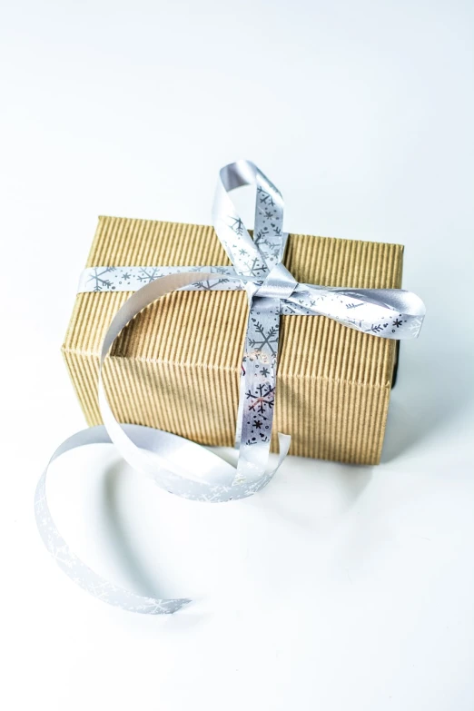 a close up of a gift box with a ribbon, a stock photo, golden and silver colors, with a white background, modern photo, product introduction photo