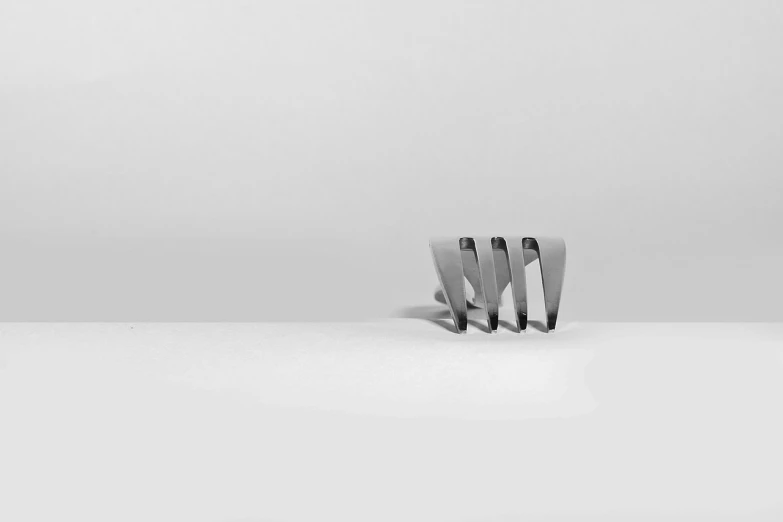 a fork sitting on top of a white table, an abstract sculpture, minimalism, 1 4 mm, metal jaw, in a row, v - fin