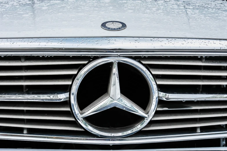 a close up of a mercedes logo on a car, by Thomas Bock, shutterstock, precisionism, with a white muzzle, taken on a 1990s camera, in style of mike savad”, icy