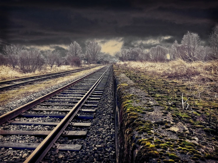 a train track with a cloudy sky in the background, a picture, flickr, realism, dark ruins landscape, computer wallpaper, cold light, low-contrast