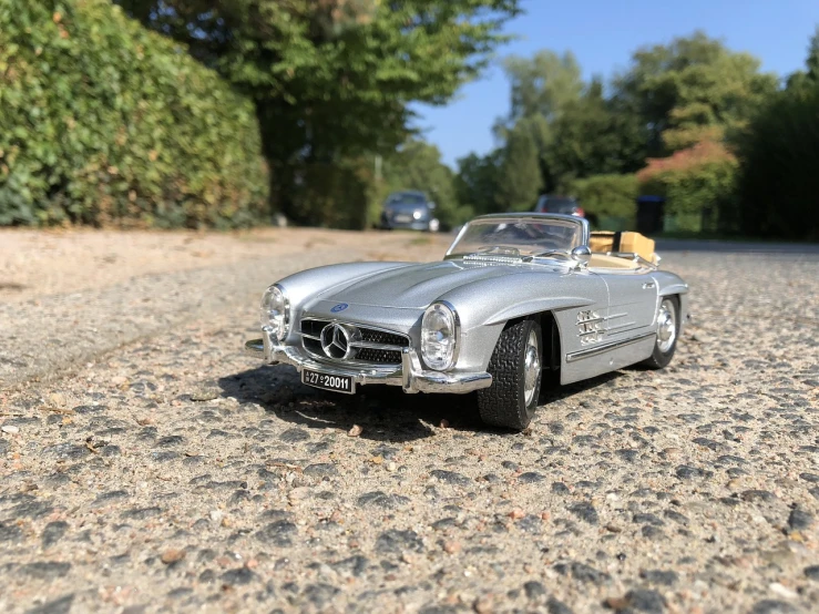 a silver toy car sitting on top of a gravel road, a portrait, wolfgang lettl highly detailed, 🕹️ 😎 🔫 🤖 🚬, speedster, amazing and immaculate scale