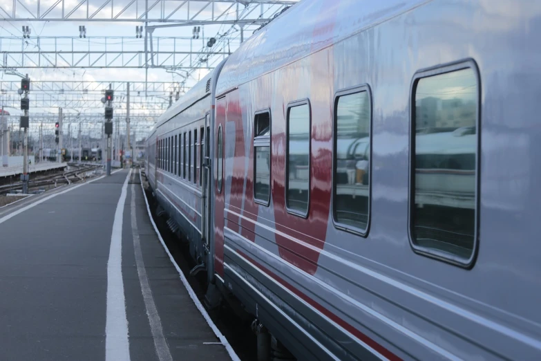 a train traveling down train tracks next to a platform, by karlkka, shutterstock, silver white red details, russian, big windows, img _ 9 7 5. raw