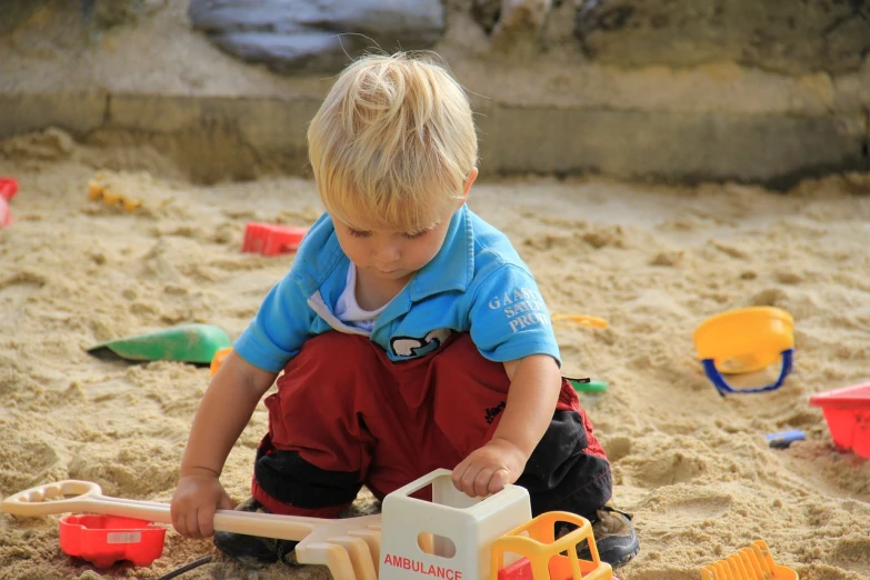 a little boy that is playing in the sand, by Edward Corbett, pexels, figuration libre, building blocks, a blond, activity play centre, playing with a small firetruck