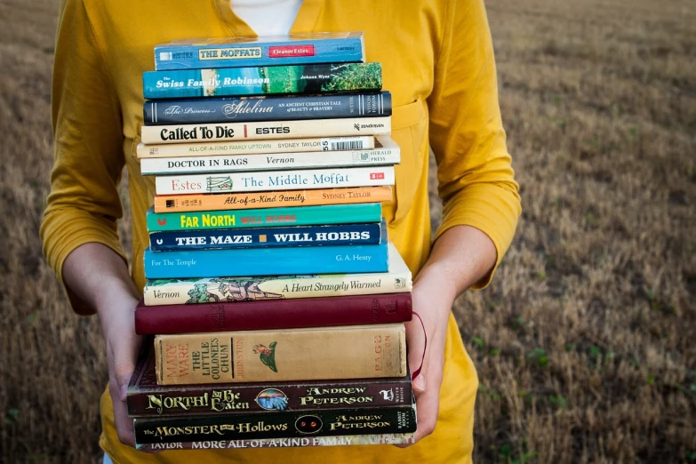 a person holding a stack of books in their hands, national geographic ”, field, a broad shouldered, skinny