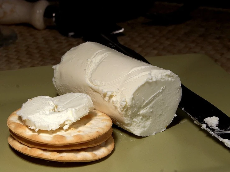 a knife sitting on top of a cracker next to a piece of cheese, a picture, by Adam Chmielowski, flickr, whipped cream, shiny white skin, half goat, white!!