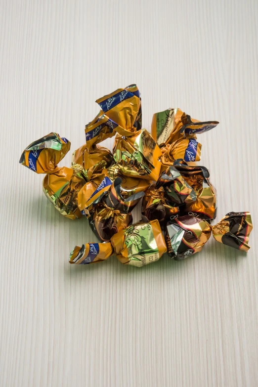 a pile of candy sitting on top of a table, a picture, inspired by Josef Šíma, gold and indigo, folds, fleks, caramel