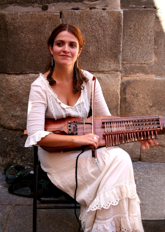 a woman sitting on a chair holding a musical instrument, inspired by Eva Gonzalès, flickr, in barcelona, bandoliers, on sidewalk, renaissance era