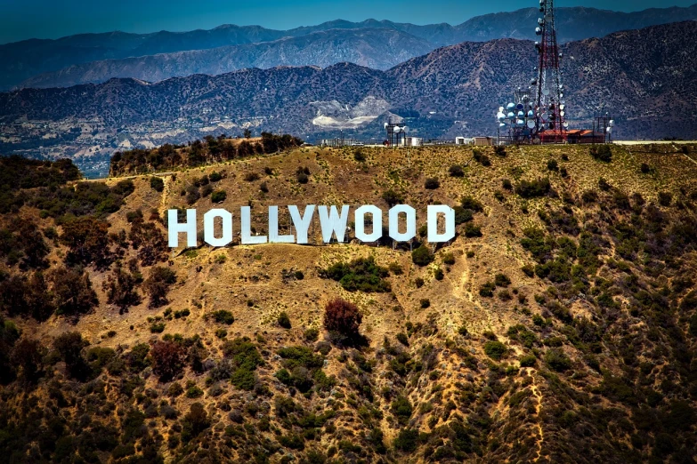 a large hollywood sign on top of a hill, a stock photo, by Howard Knotts, shutterstock, art nouveau, marvel comics dslr hdr, hd aerial photography, photograph”