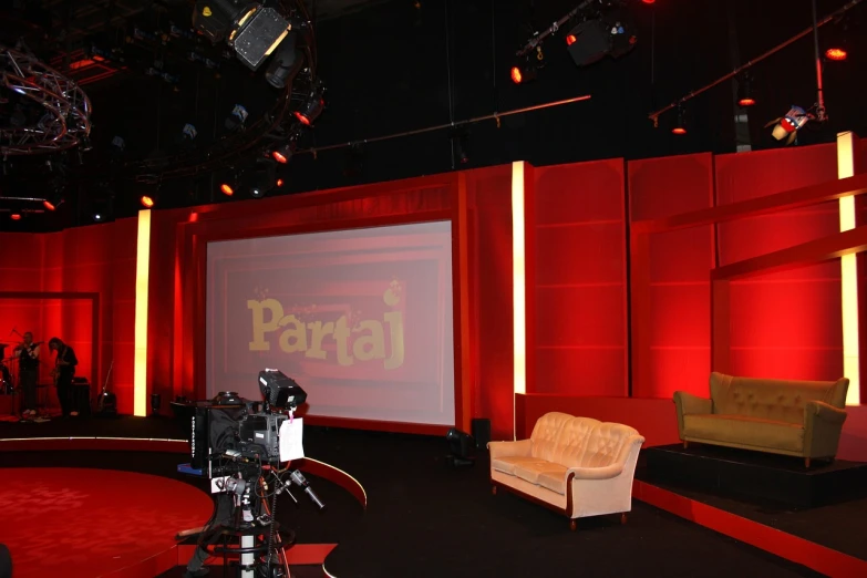 a room with couches, chairs and a projector screen, by Petr Brandl, dau-al-set, talk show, delivering parsel box, red colour palette, mattell
