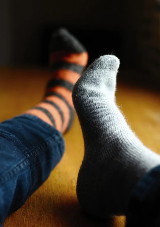 a pair of socks sitting on top of a wooden floor, by Jan Rustem, orange grey white, tight focus, blog-photo, a woman