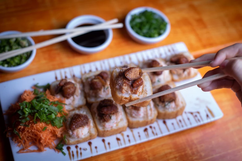 a person holding chopsticks over a plate of food, a pastel, mingei, professional food photography, nugget and sausage on plate, oceanside, crispy buns