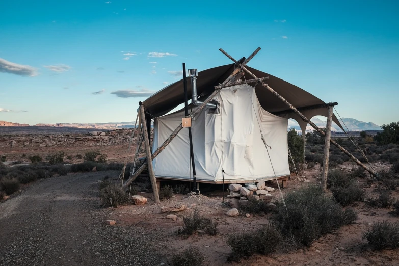 a tent sitting in the middle of a desert, a portrait, wide shot of a cabin interior, with pipes attached to it, high res photo, moab