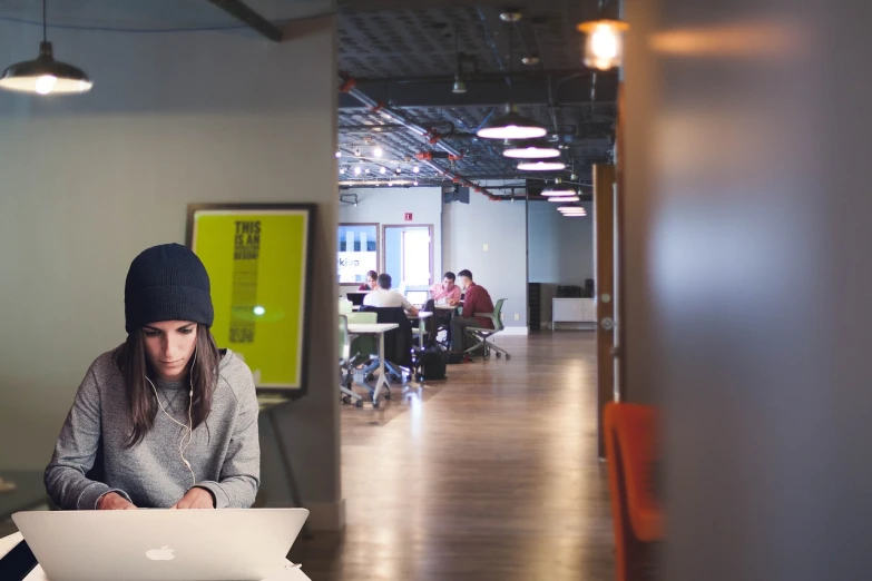 a woman sitting at a table working on a laptop, a picture, by Jason Felix, inside the building, panoramic shot, headspace, boston