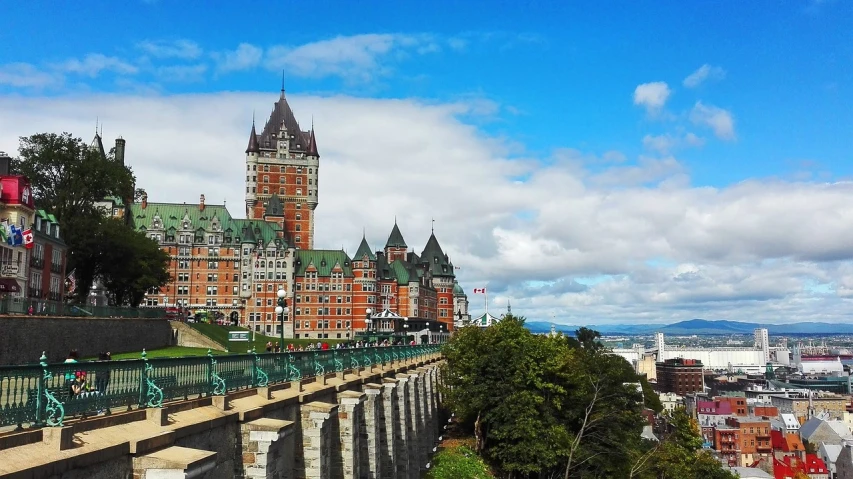 a large castle sitting on top of a lush green hillside, pexels contest winner, art nouveau, quebec, elegant walkways between towers, all buildings on bridge, family friendly