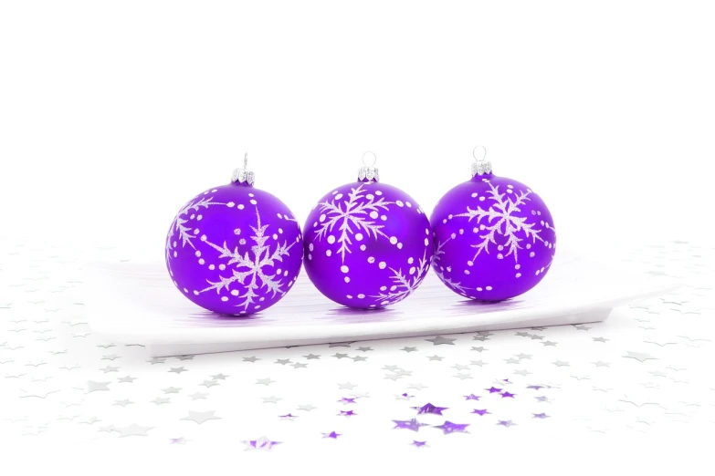 three purple christmas ornaments sitting on top of a white plate, a photo, professional product photo, white stars in the background, isolated white background, a bright