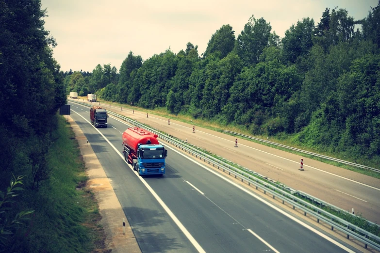 a number of trucks on a highway with trees in the background, by Dariusz Zawadzki, shutterstock, figuration libre, sparsely populated, lower saxony, very asphalt, vintage color