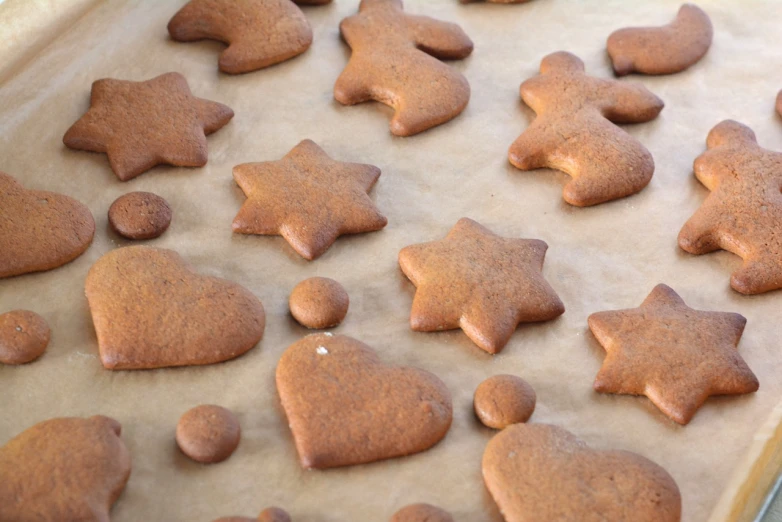 a pan filled with cookies sitting on top of a table, by Ödön Márffy, figuration libre, parchment paper, star, smooth rounded shapes, reddish - brown