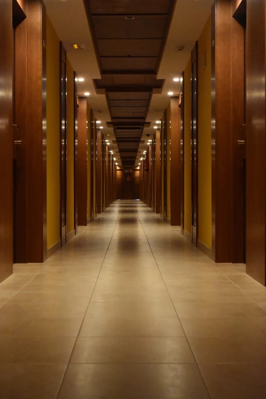 a long hallway with a clock on the wall, a stock photo, by Andrei Kolkoutine, high-end onsen, brown atmospheric lighting, rows of doors, anomalisa