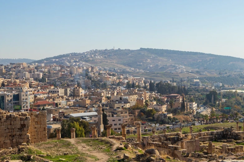 a view of a city from the top of a hill, les nabis, ancient ruins background, hamar, sunny, in a city with a rich history