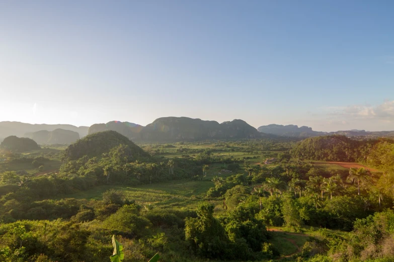a train traveling through a lush green countryside, cuban setting, mountains and sunset!!, panorama of crooked ancient city, f / 3