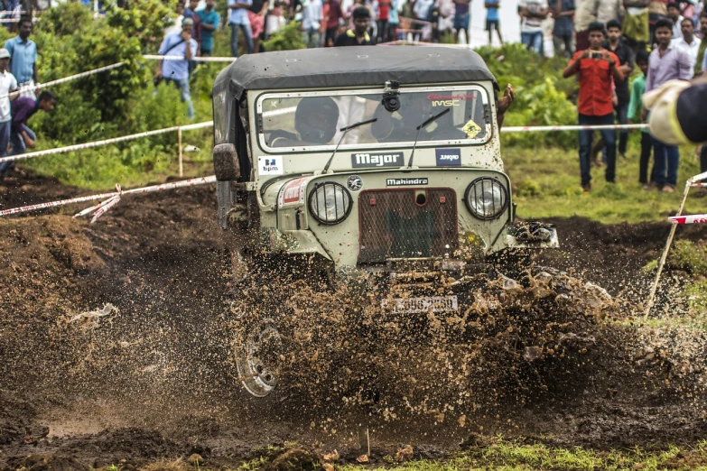 a jeep driving through mud in front of a crowd, a portrait, mingei, retro vibe, pullitzer winning, india, in a race competition